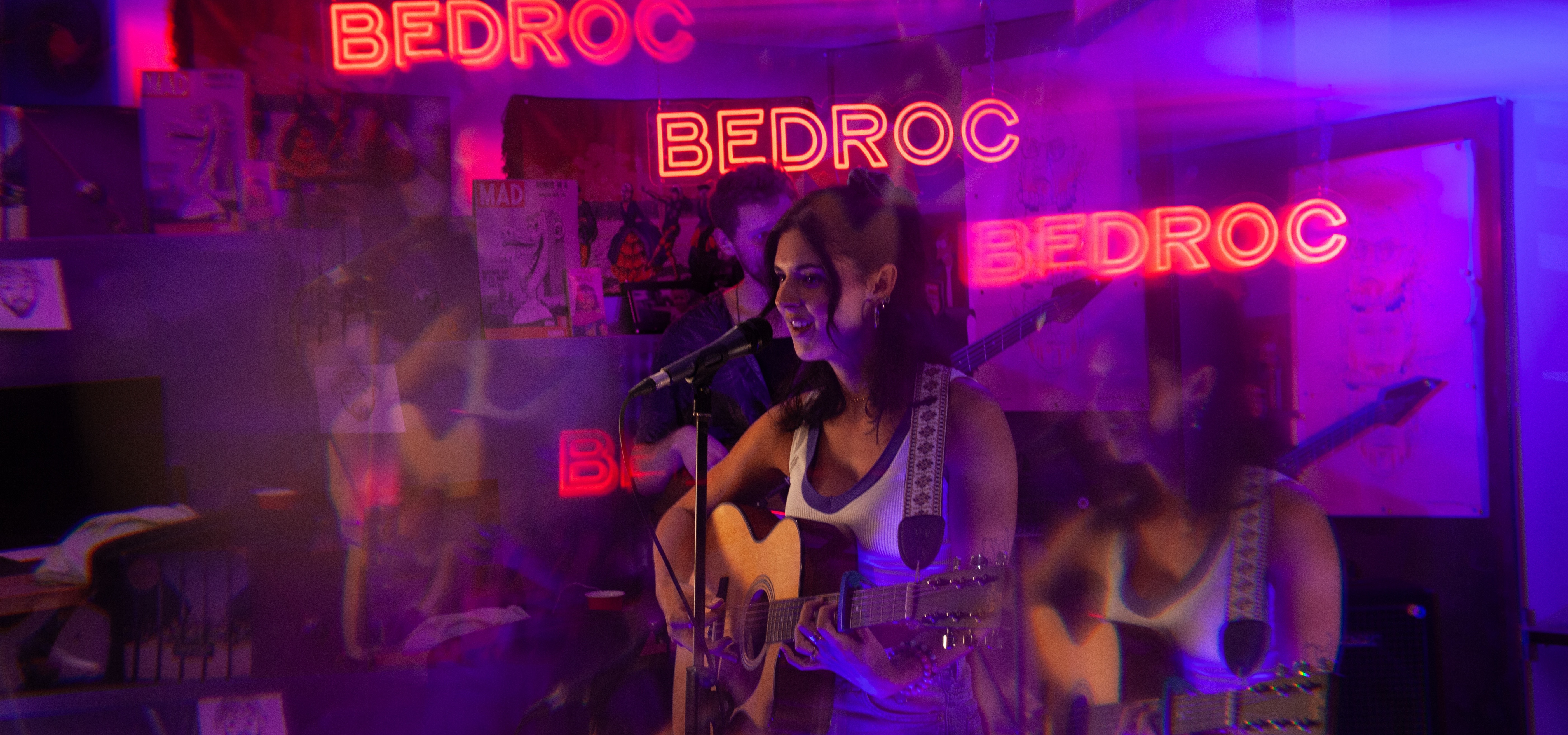 Live performance at Bedroc - Female performer with acoustic guitar in front of neon Bedroc signs
